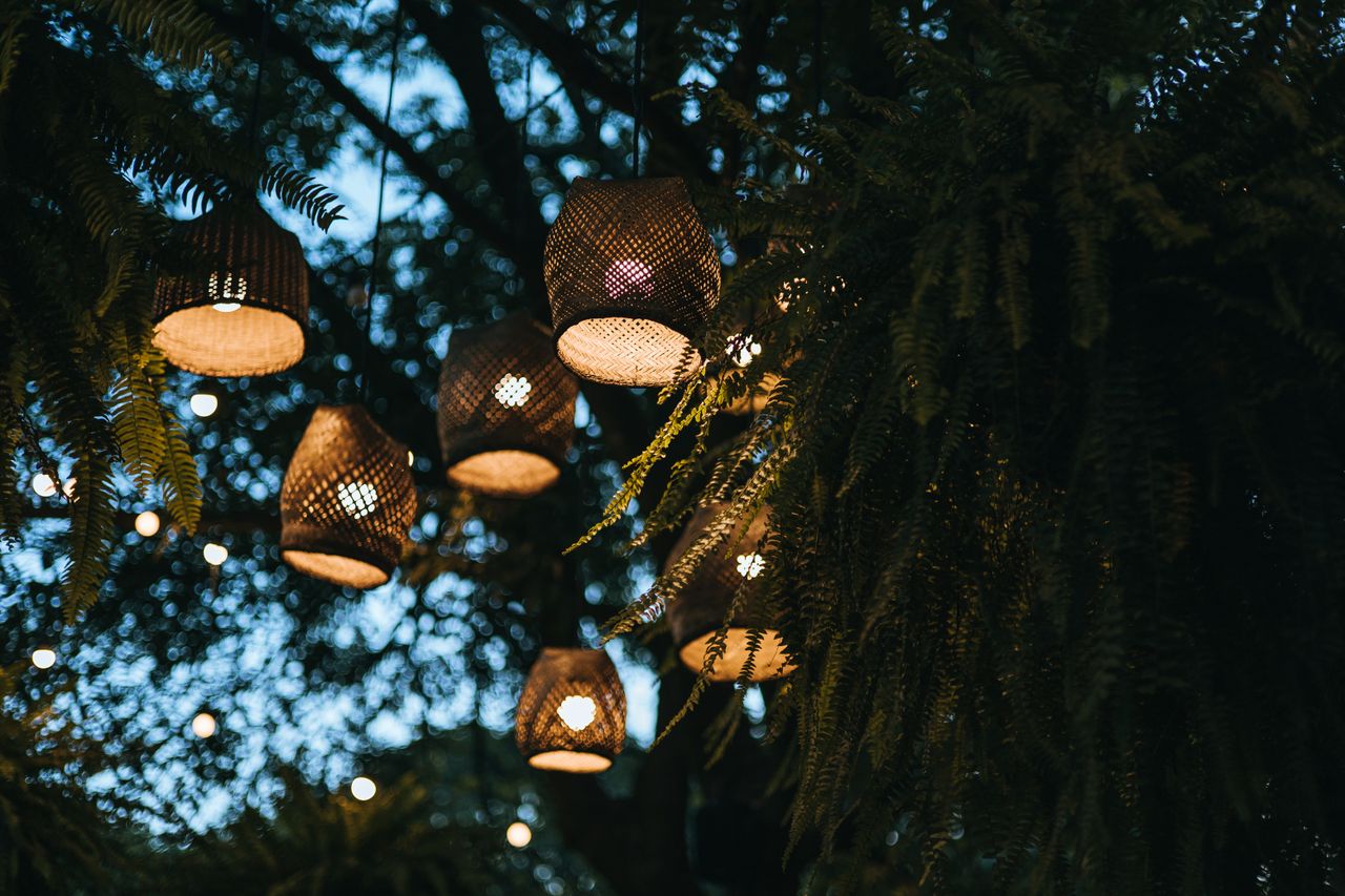 gallery-02 Hanging golden lanterns in a lush, evening garden create a magical ambiance.
