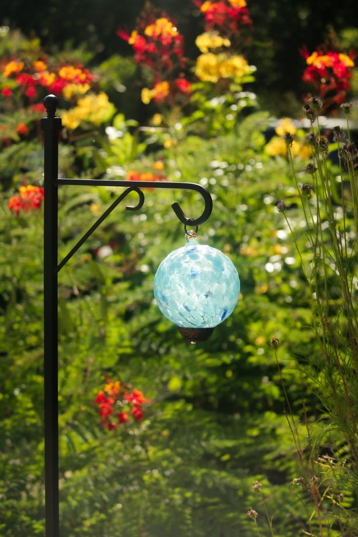 Mastering the First Impression: Your intriguing post title goes here Vibrant garden scene featuring a decorative blue glass lantern with abundant flowers in the background.